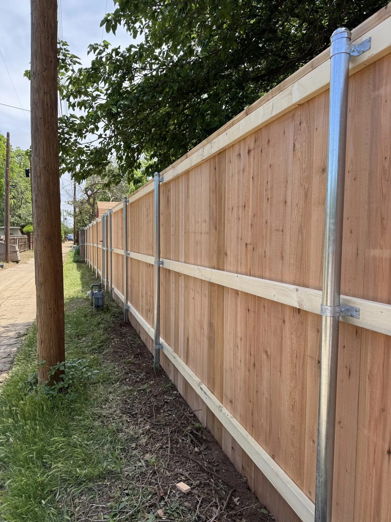 Galvanized steel posts and three rails on the back side of a new cedar fence built by Hudson Fence Company in Lubbock, TX