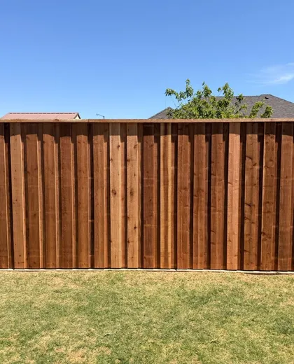Stained capped board-on-board cedar fence across a backyard in Lubbock, TX