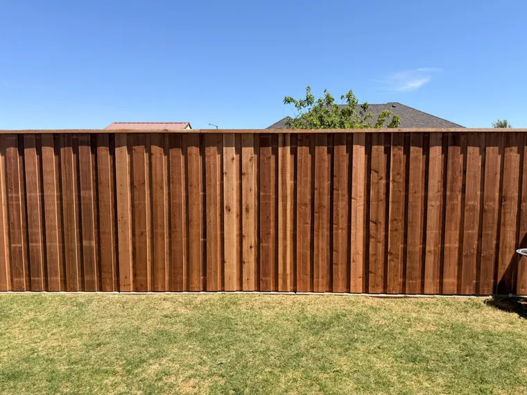 Stained capped board-on-board cedar fence across a backyard in Lubbock, TX