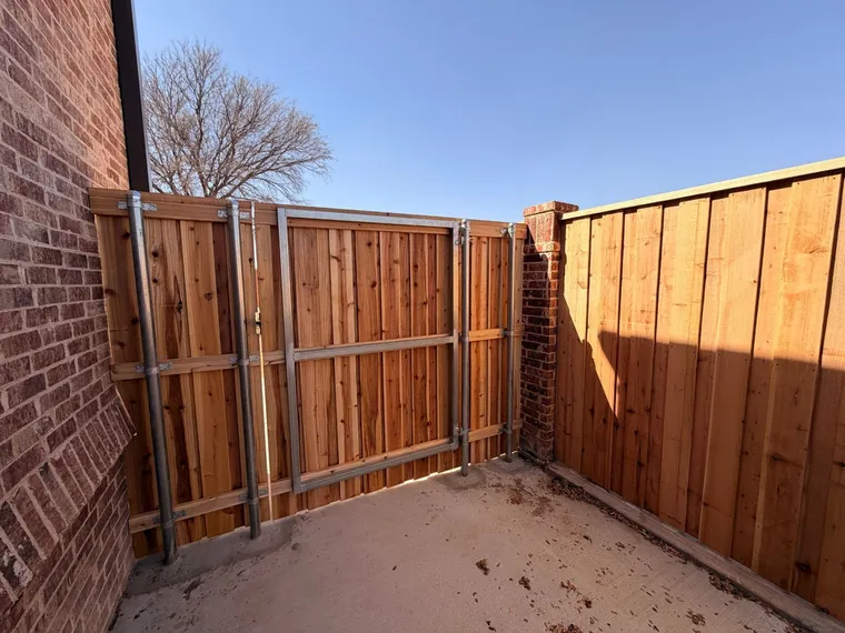 Steel gate frame on a capped cedar fence gate inside a concrete courtyard
