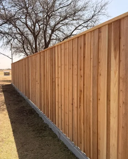Capped cedar board-on-board fence on a concrete mow curb