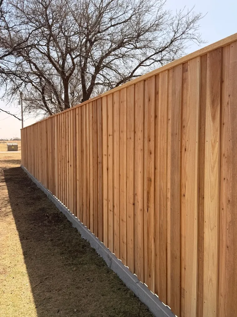 Capped cedar board-on-board fence on a concrete mow curb