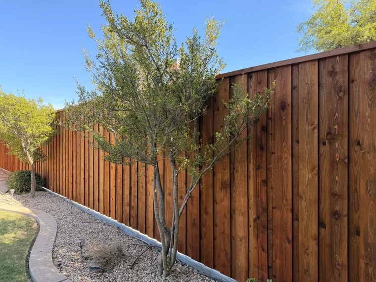 Stained cedar board-on-board fence behind a landscaped rock bed