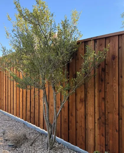 Stained cedar board-on-board fence behind a landscaped rock bed