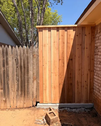 New capped cedar fence section on a curb next to an old neighbor fence