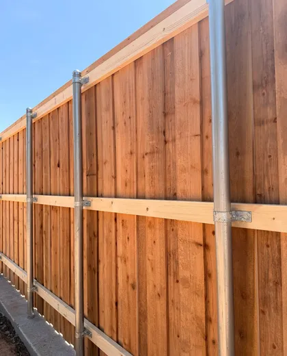 Back side of a capped cedar fence with galvanized steel posts and rails