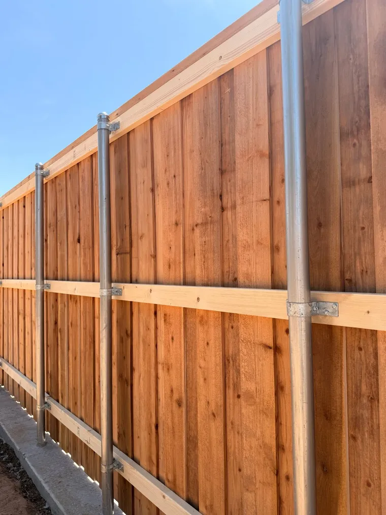 Back side of a capped cedar fence with galvanized steel posts and rails