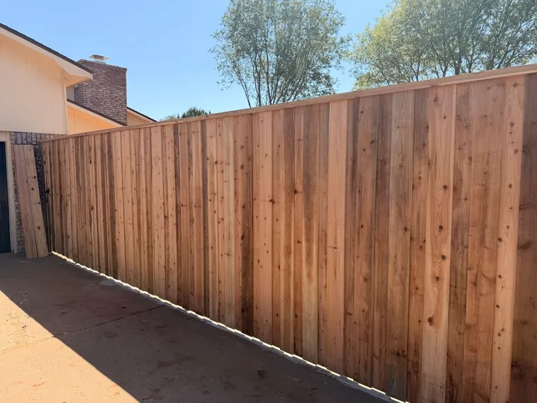 New capped cedar board-on-board fence along a driveway