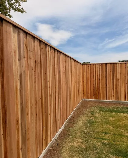 Capped cedar fence corner on a concrete curb around a new backyard