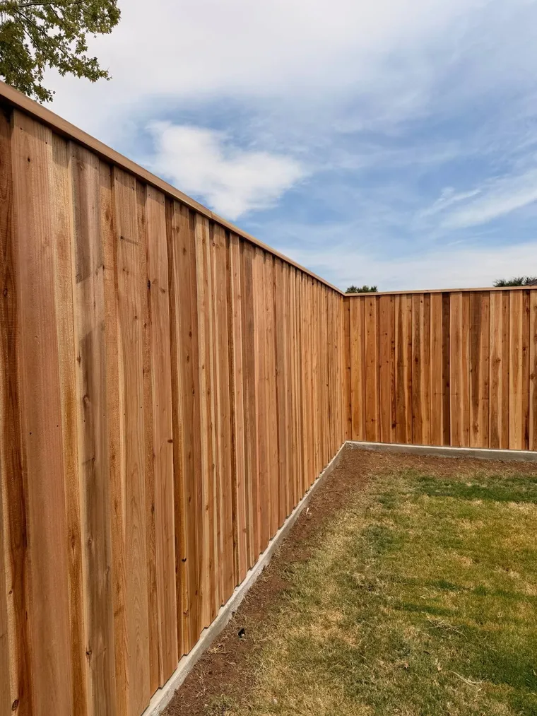 Capped cedar fence corner on a concrete curb around a new backyard