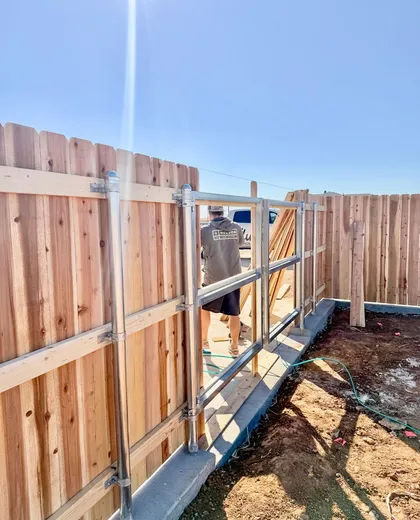 Hudson Fence Company crew building a steel-framed double drive gate on a dog ear cedar fence