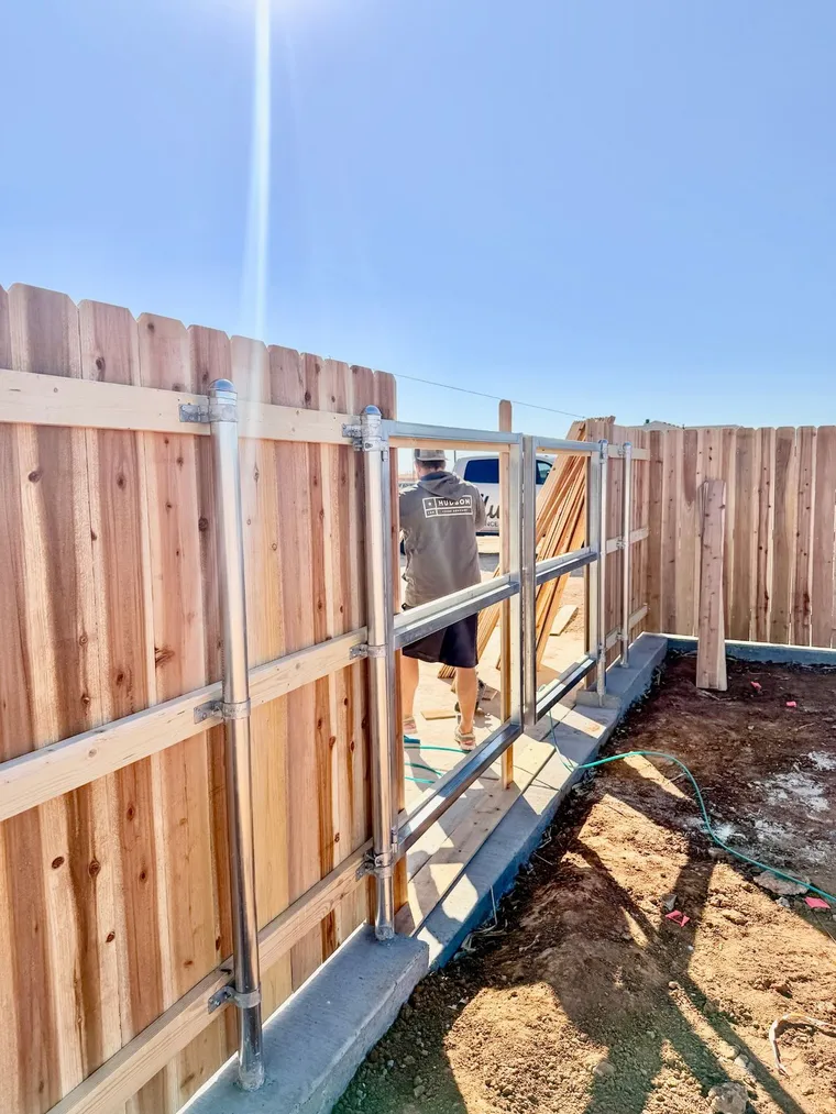 Hudson Fence Company crew building a steel-framed double drive gate on a dog ear cedar fence