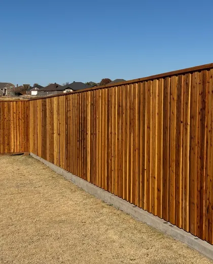 Stained capped cedar board-on-board fence on a concrete curb in a new neighborhood