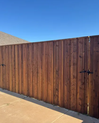 Stained capped cedar fence and walk gate along a concrete patio