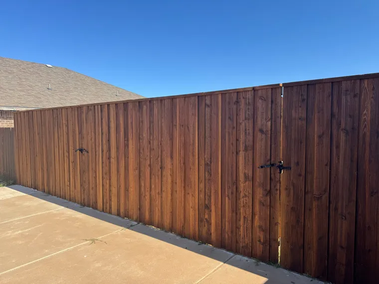 Stained capped cedar fence and walk gate along a concrete patio