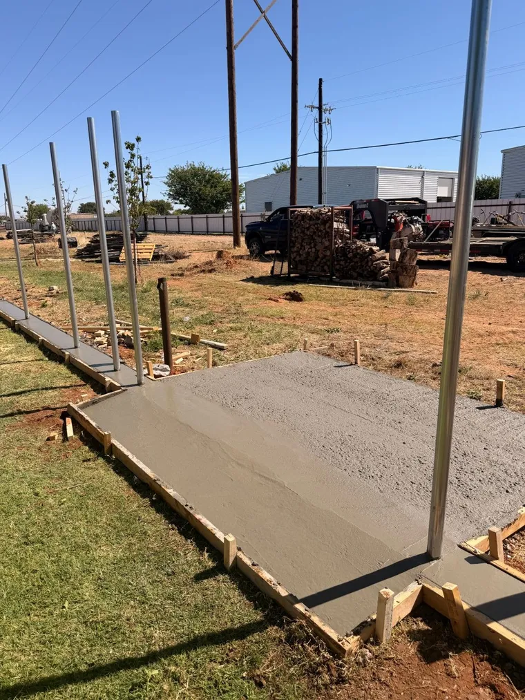 Concrete pad tied into a fence curb with steel posts at a commercial property