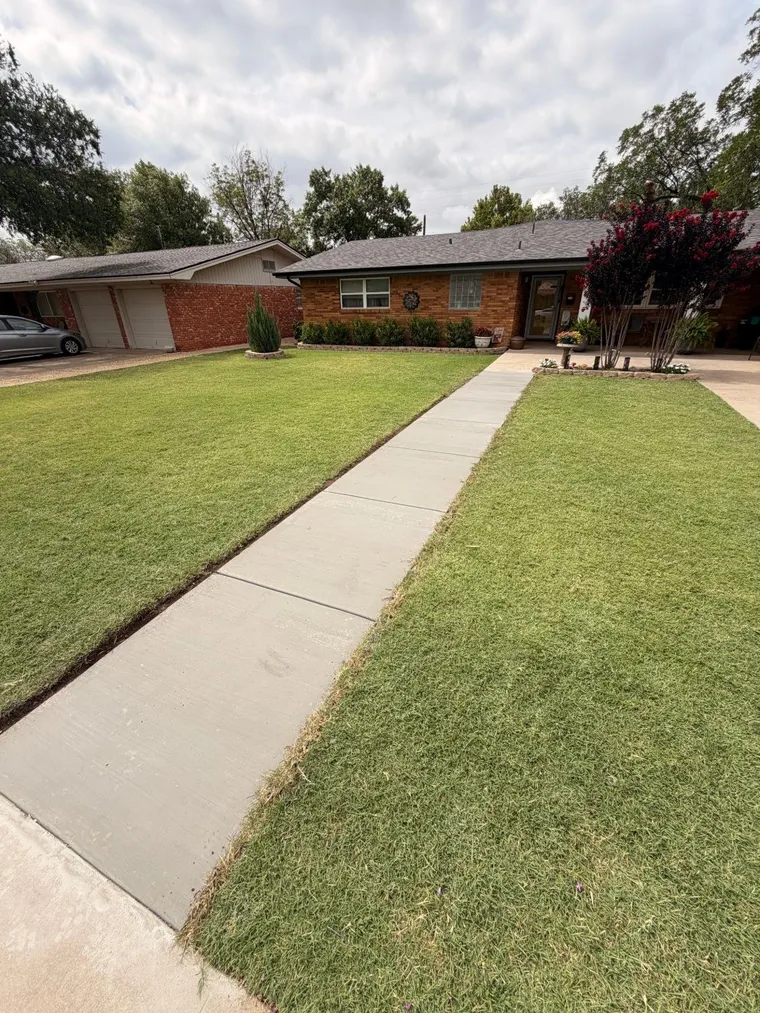 Finished concrete front sidewalk leading to a brick home in Lubbock, TX