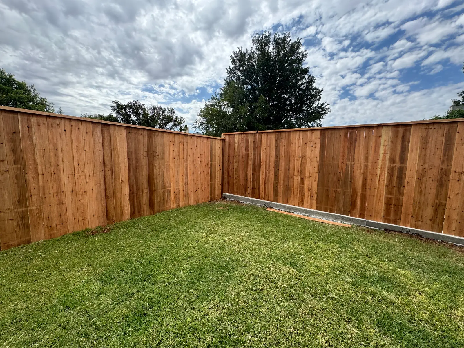 A completed cedar privacy fence corner in a Lubbock, TX backyard, installed by Hudson Fence Company