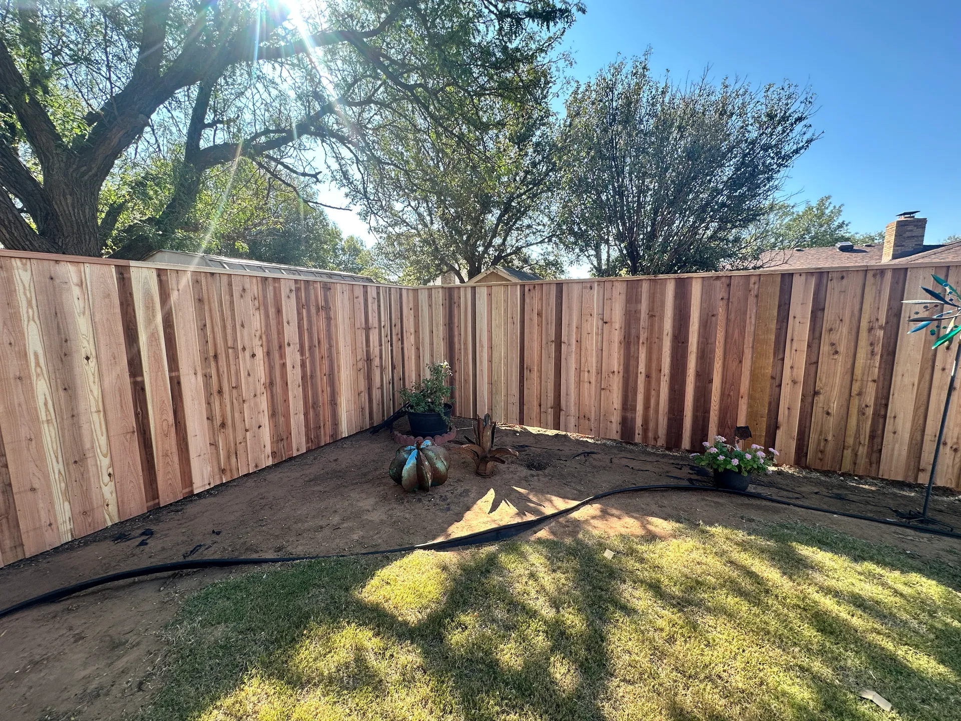A completed cedar privacy fence corner in a Lubbock, TX backyard, installed by Hudson Fence Company
