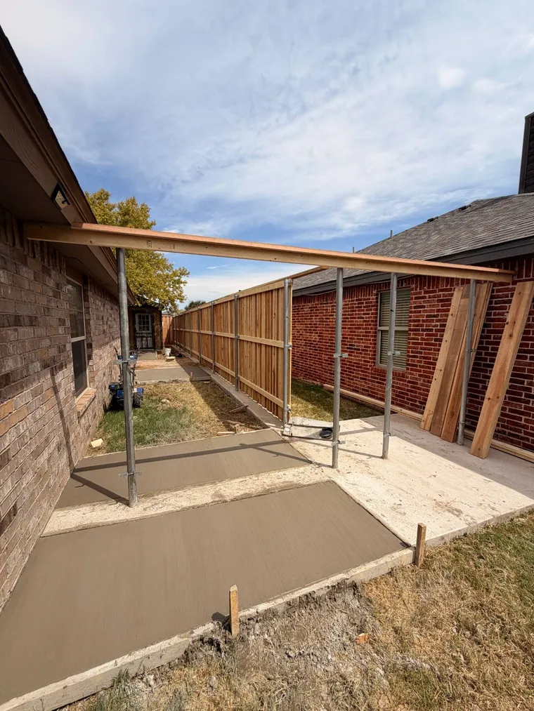 Side yard concrete walkways poured between two homes alongside a new cedar fence on steel posts